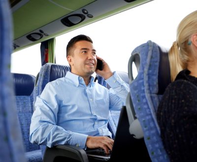 transport, tourism, business trip and people concept - smiling man with smartphone and laptop calling in travel bus